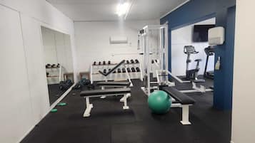 A gym with weightlifting equipment, exercise balls, and treadmills.