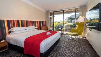 A hotel room with a large bed, a desk, a chair, and a TV.