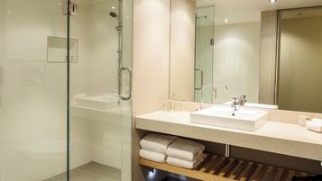 Une salle de bain moderne dotée d’une douche à parois de verre, d’un grand miroir et d’un meuble-lavabo à deux vasques.