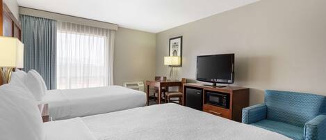 Una habitación de hotel con dos camas, un escritorio con computadora, televisión y un sillón azul.