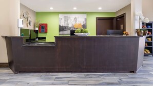 A reception desk with a green wall, a cityscape painting, and a plant on the counter. - Best Western near Lackland AFB/SeaWorld (San Antonio)