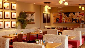 A restaurant with booths and tables, framed artwork on the walls, and hanging pendant lights. - Bishopstrow Hotel & Spa (Warminster)