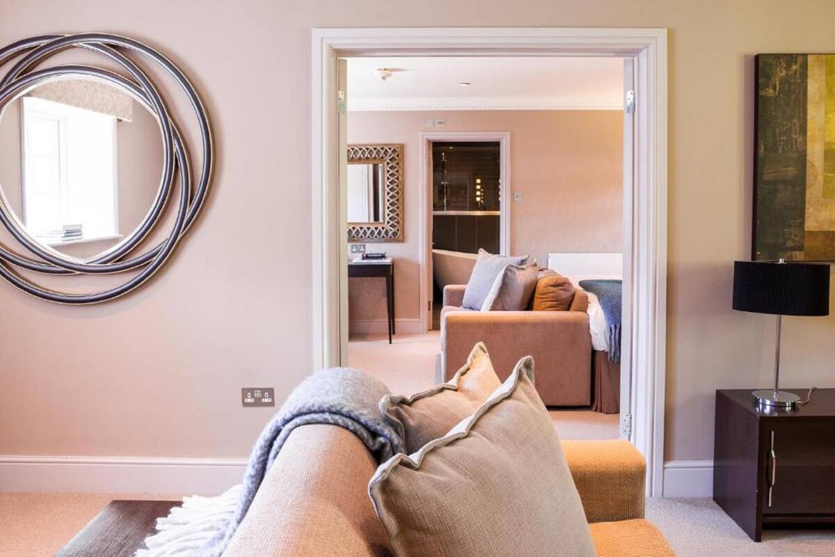 A modern living room with a sofa, a round mirror, and a painting on the wall.