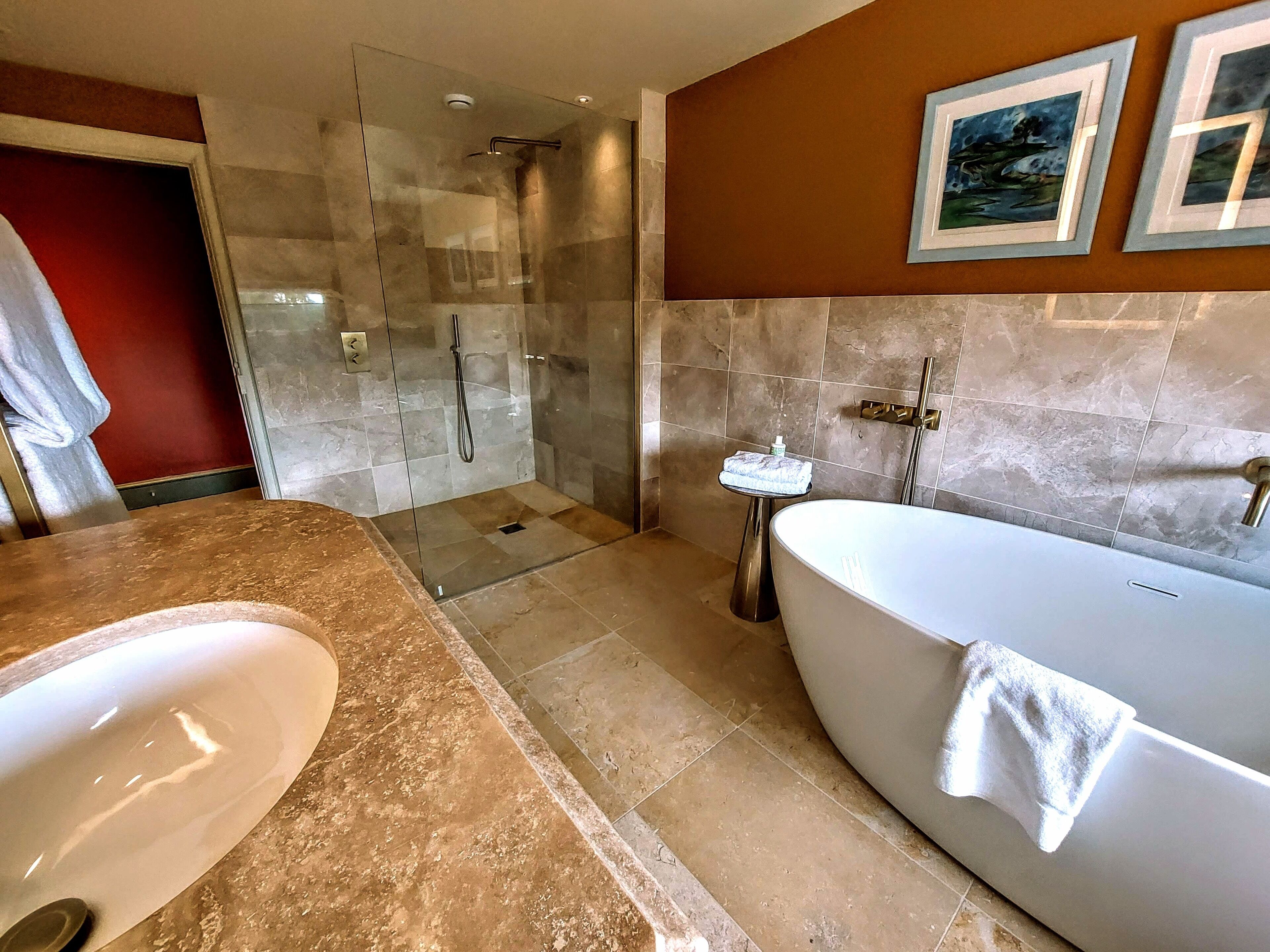 Un baño moderno con ducha acristalada, una bañera independiente y un tocador con lavamanos.