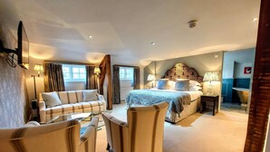 A hotel room with a bed, a sofa, two armchairs, a bedside table, and a lamp. - Bishopstrow Hotel & Spa (Warminster)