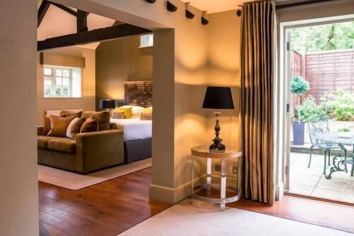 A room with a bed, a sofa, a lamp, and a view of the outdoors.