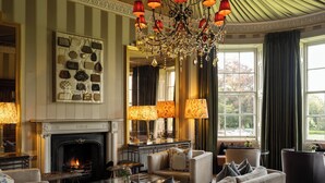 A luxurious living room with a fireplace, elegant furniture, and a chandelier. - Bishopstrow Hotel & Spa (Warminster)