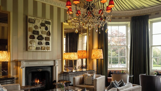 Un salón lujoso con chimenea, muebles elegantes y un candelabro.