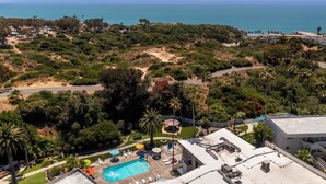 Un resort con piscina, asientos al aire libre y vista al océano.