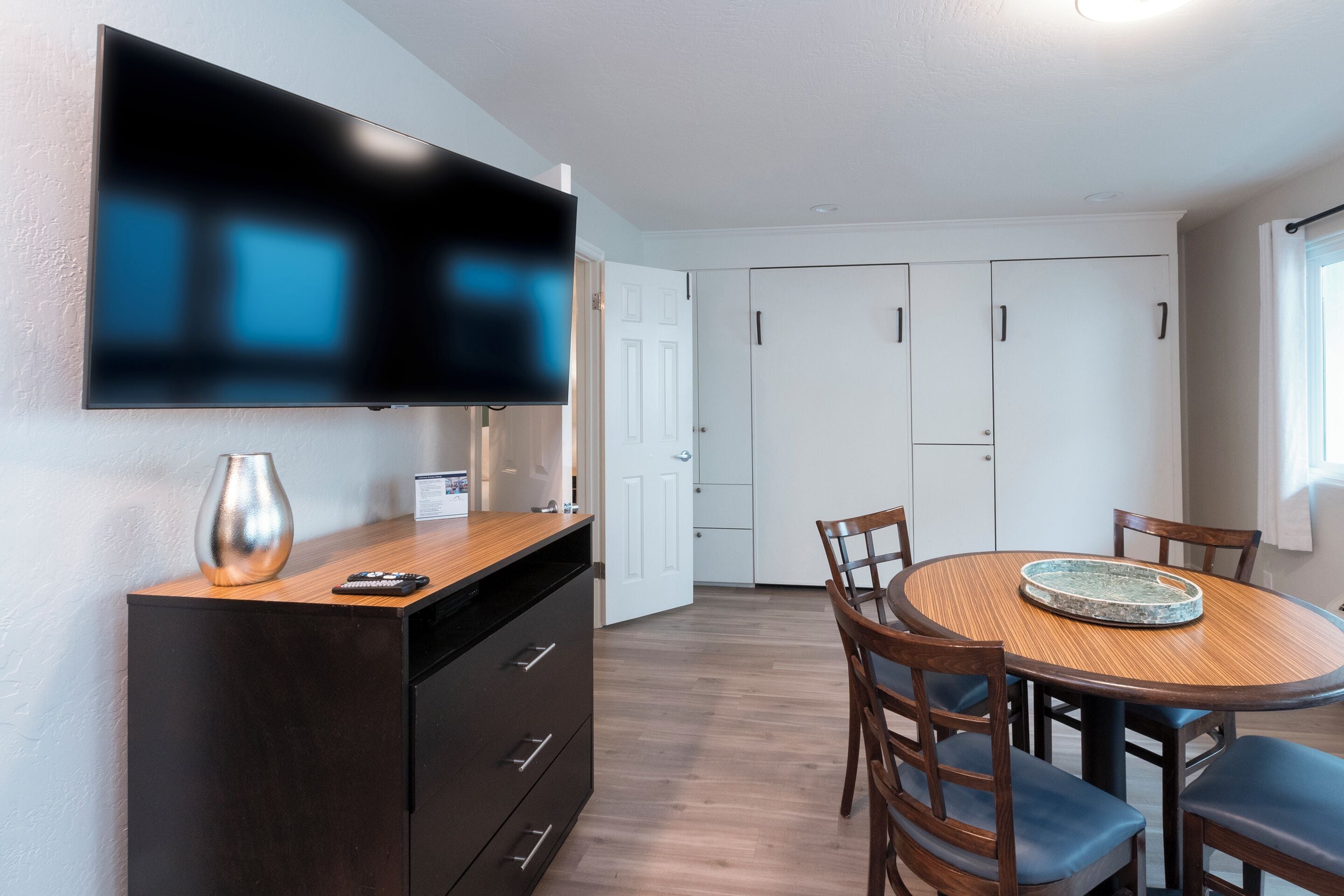 Una cocina moderna con una televisión de pantalla plana sobre una mesa de madera rodeada de sillas.