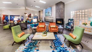 Un lobby amplio con sillones verdes, una mesa de centro y una chimenea.