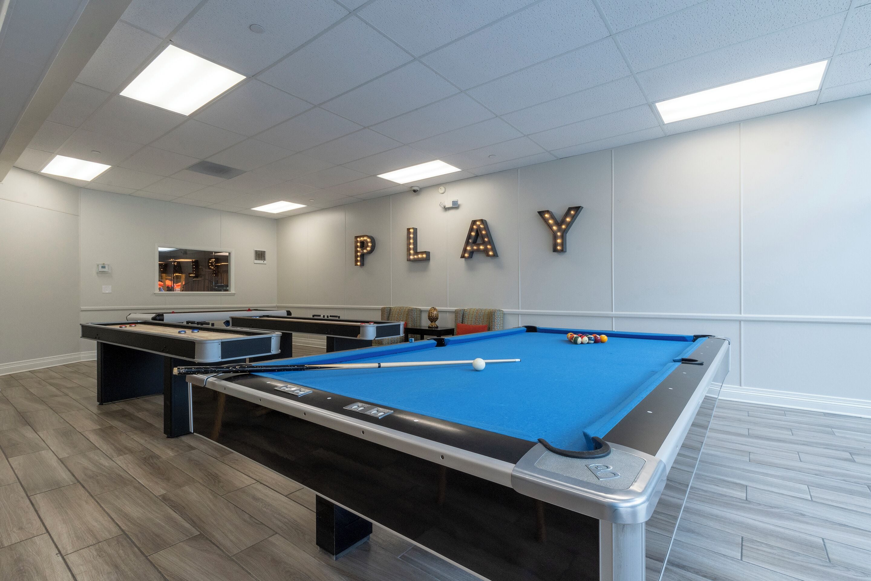 Een pooltafel met een blauwe viltkleed, een tafelvoetbalspel en een biljarttafel.
