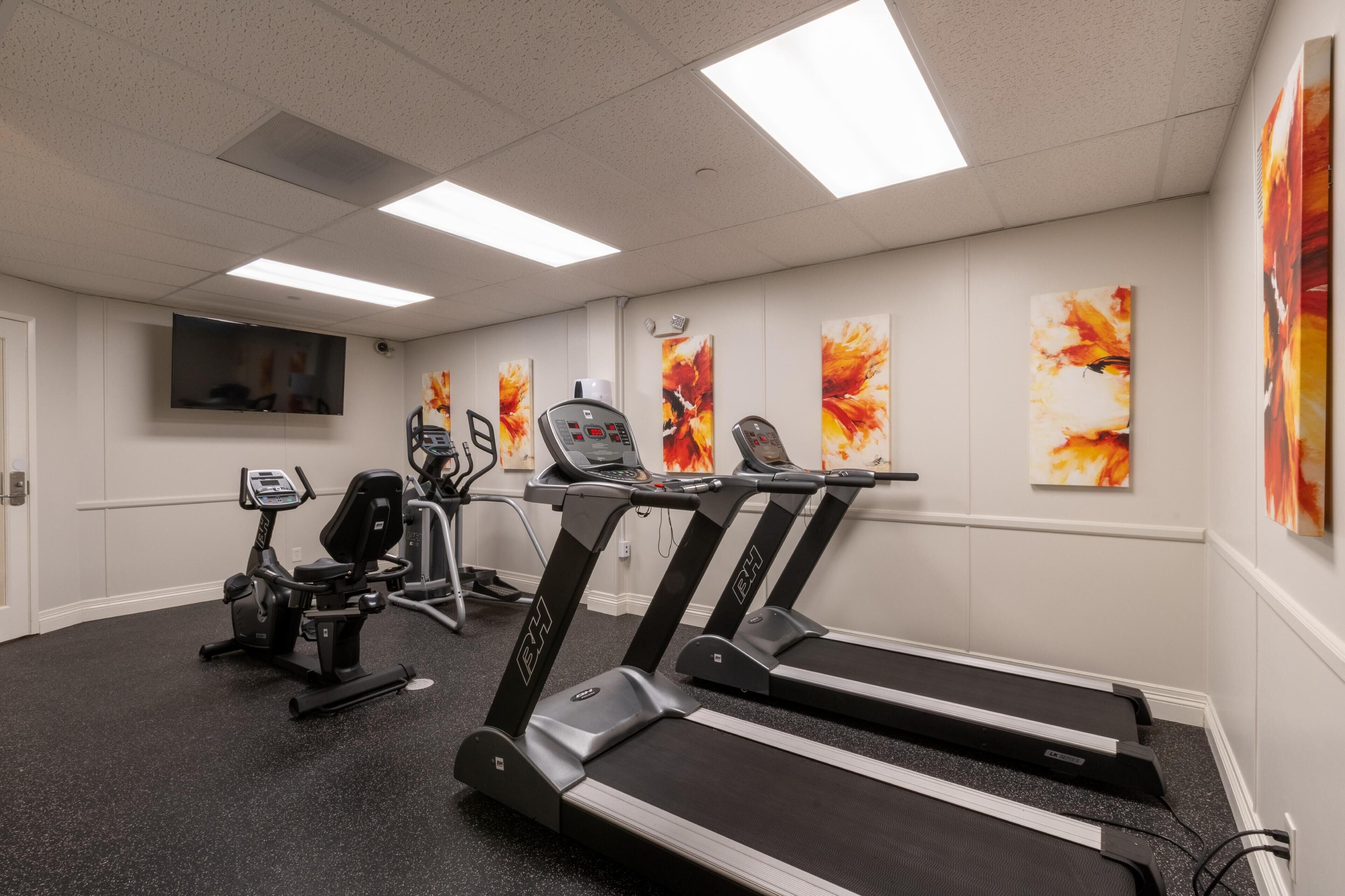 A gym with treadmills, an elliptical, and a stationary bike.