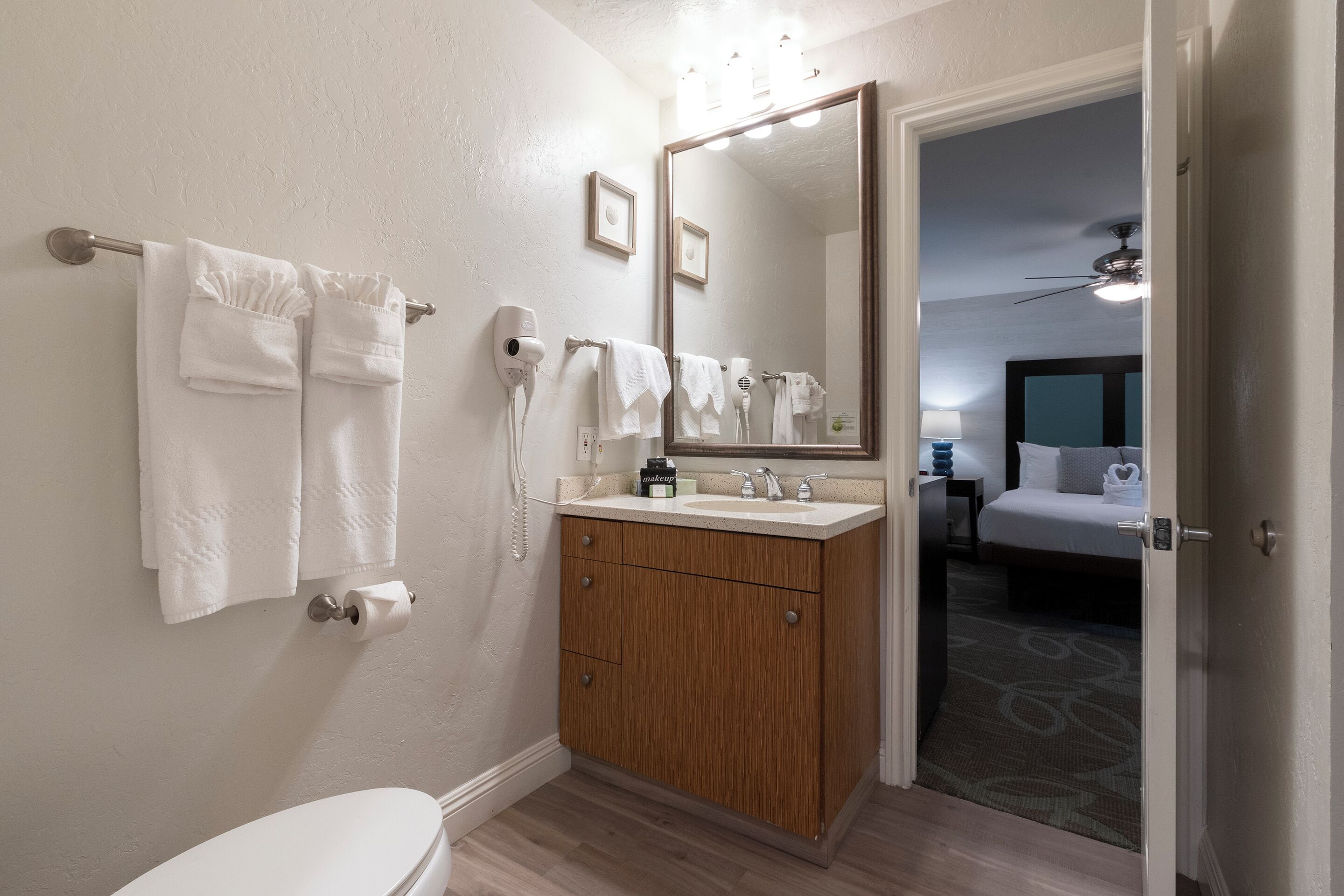 A bathroom with a toilet, a sink with a vanity, a mirror, and a towel rack.