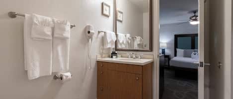 A bathroom with a toilet, a sink with a vanity, a mirror, and a towel rack.