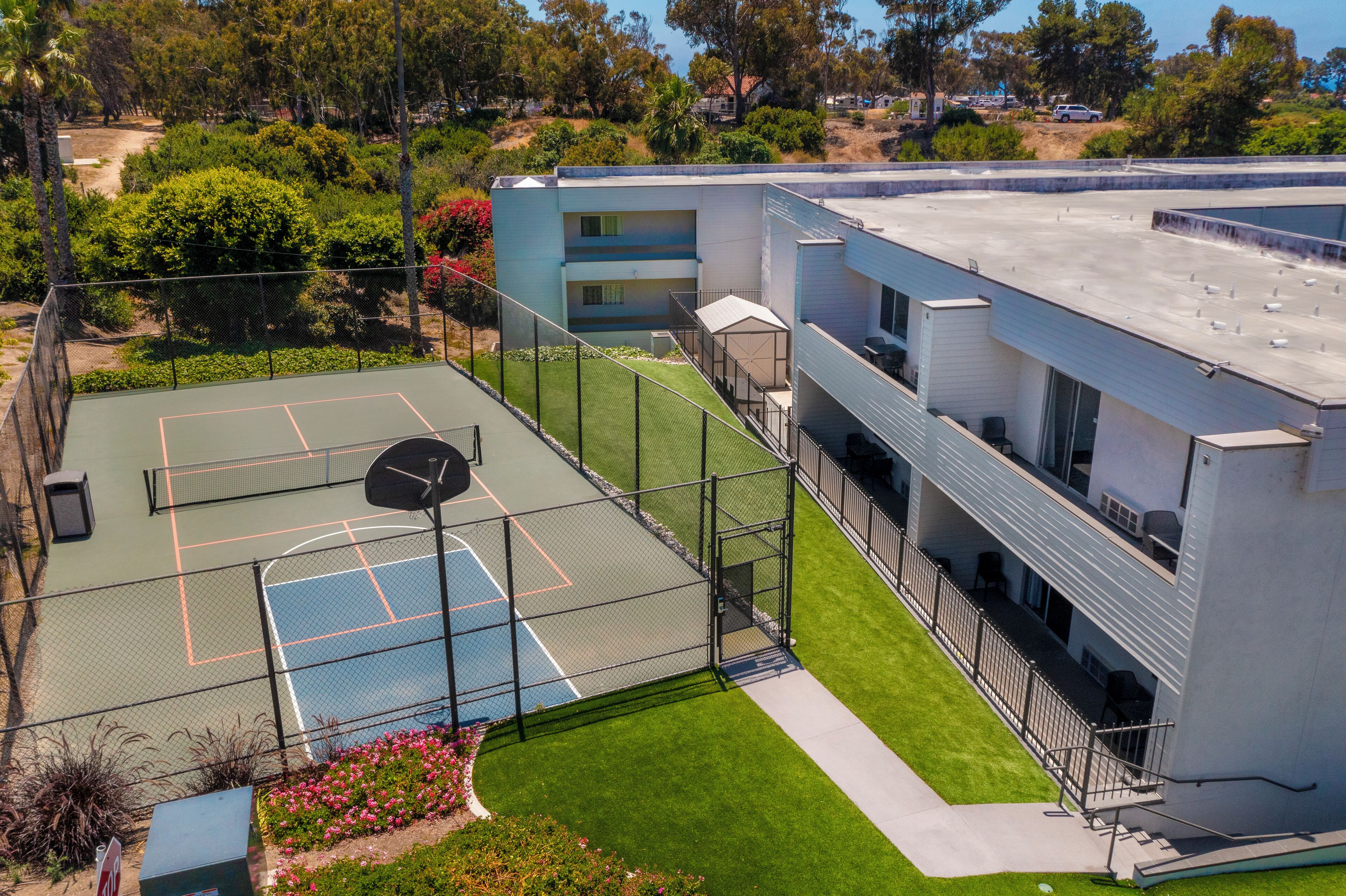 Ein mehrstöckiges Gebäude mit Tennisplatz und Poolbereich.