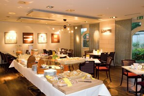 A hotel dining area with a buffet setup, including bread, pastries, and beverages. - Hotel Conti Dietikon (Dietikon)