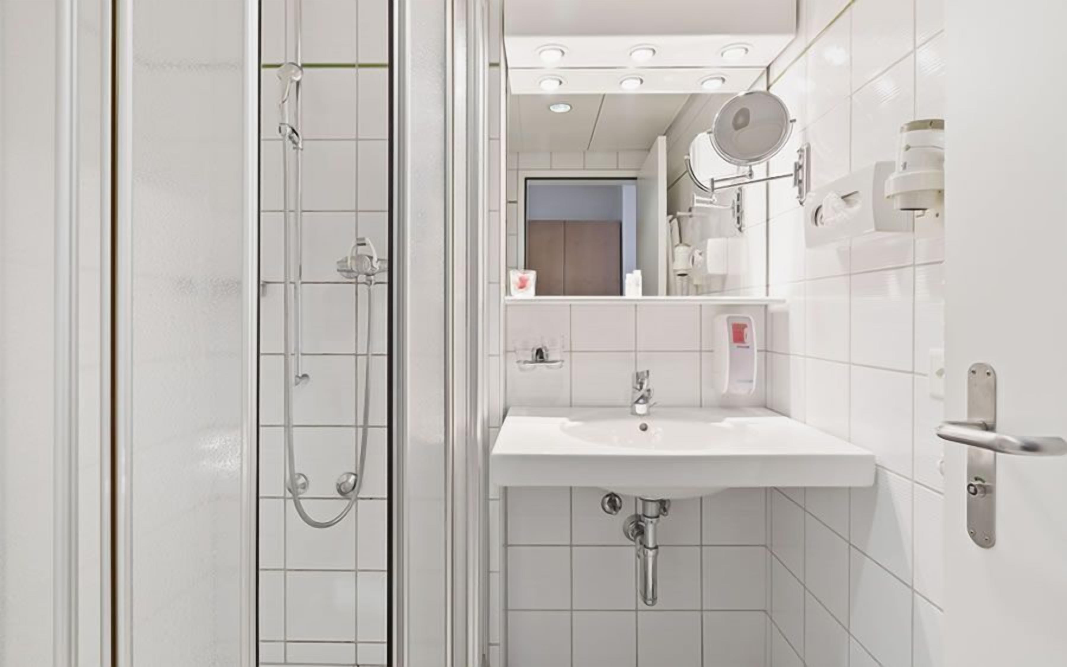 A modern bathroom with a glass shower enclosure, a white sink, and a mirror above the sink.