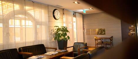 A conference room with a long table, several chairs, a clock on the wall, and a potted plant.