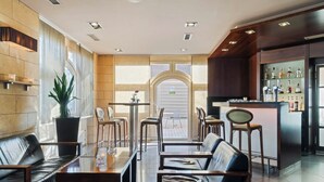 A modern hotel lobby with leather seating, a bar area, and a view through large windows.