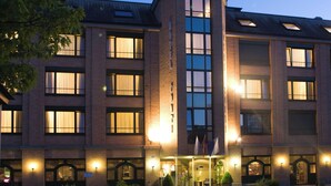 A multi-story hotel with a central tower, large windows, and a well-lit entrance.