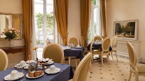 Une salle à manger avec une table mise pour quatre personnes, des chaises, un vase rempli de fleurs et un tableau accroché au mur.