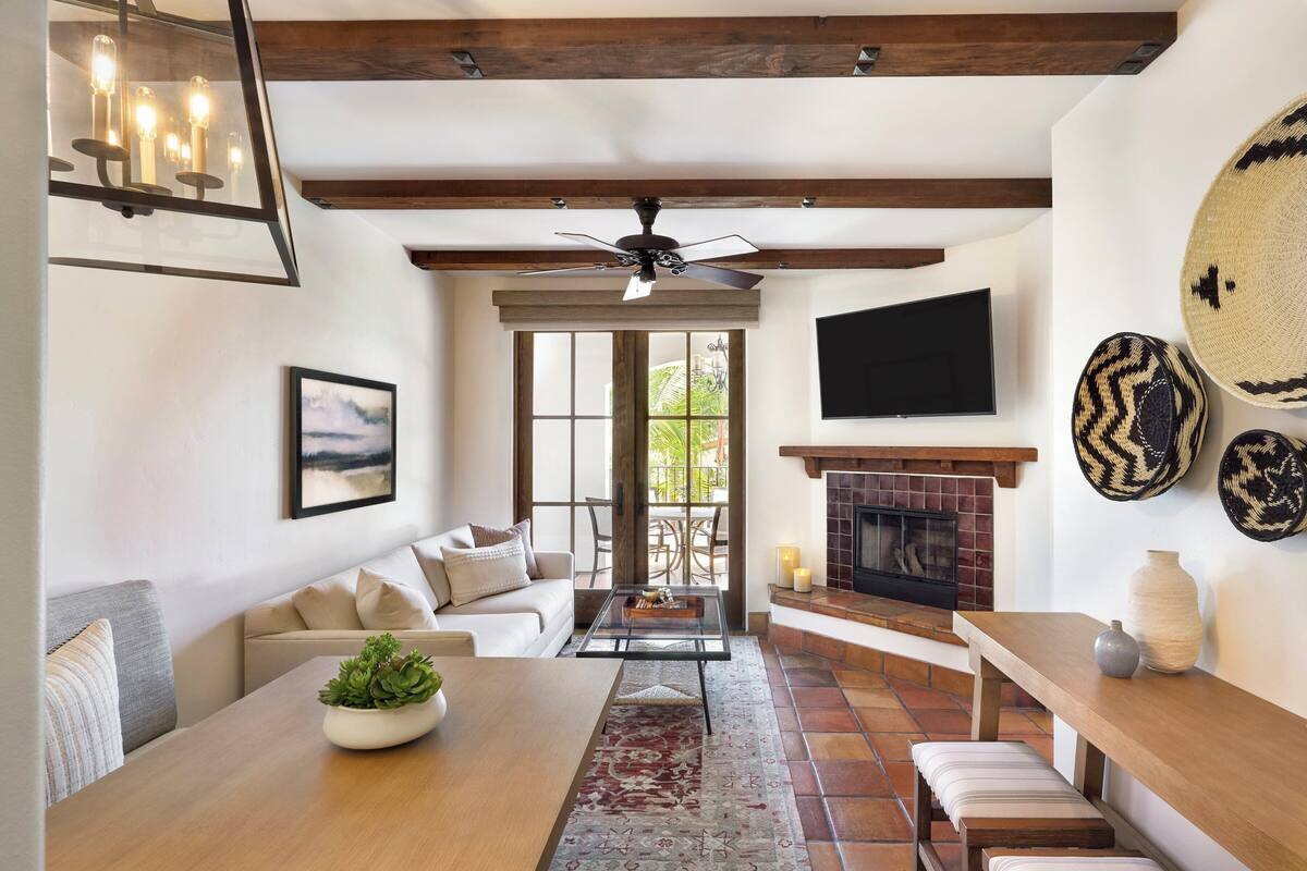A spacious living room with a fireplace, a sofa, a coffee table, and a television mounted on the wall.