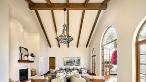 A spacious living room with a fireplace, a chandelier, and a large window with a view of the outdoors. - Omni La Costa Resort & Spa Carlsbad (Carlsbad)