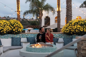 A well-maintained garden with palm trees and a building with a red-tiled roof. at Omni La Costa Resort & Spa Carlsbad