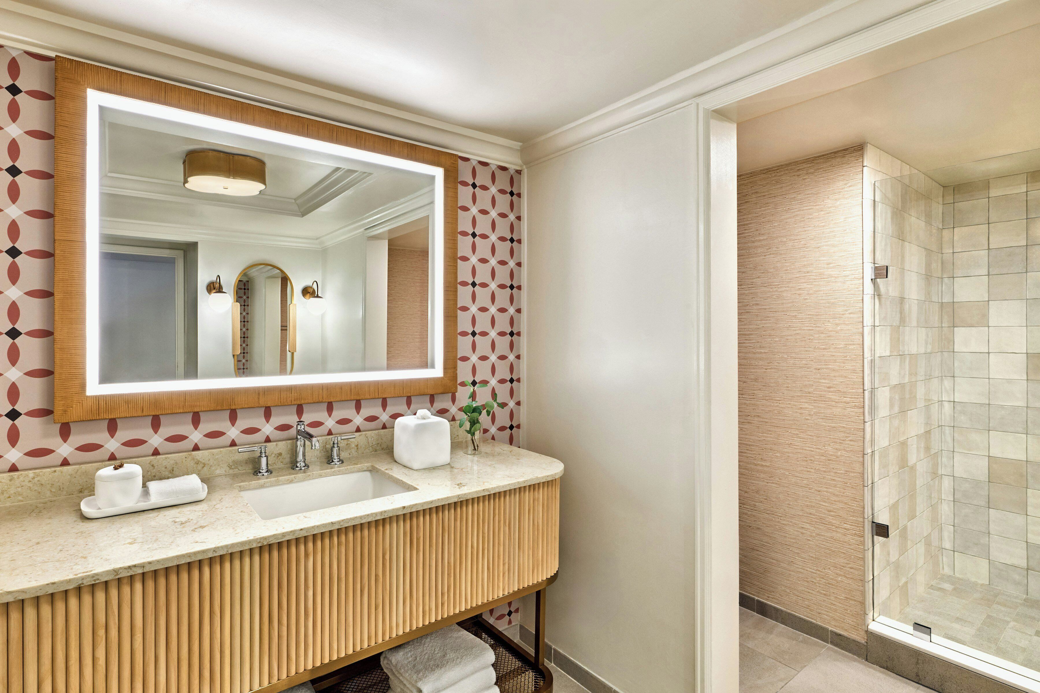 Un baño moderno con un espejo grande, un lavabo y una zona de ducha.