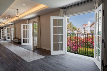 A bedroom with a large bed, a view of a golf course, and a balcony with chairs and a table. at Omni La Costa Resort & Spa Carlsbad