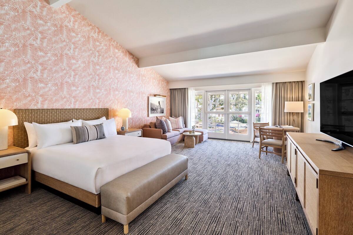 A hotel room with a large bed, a sofa, a desk, and a television.