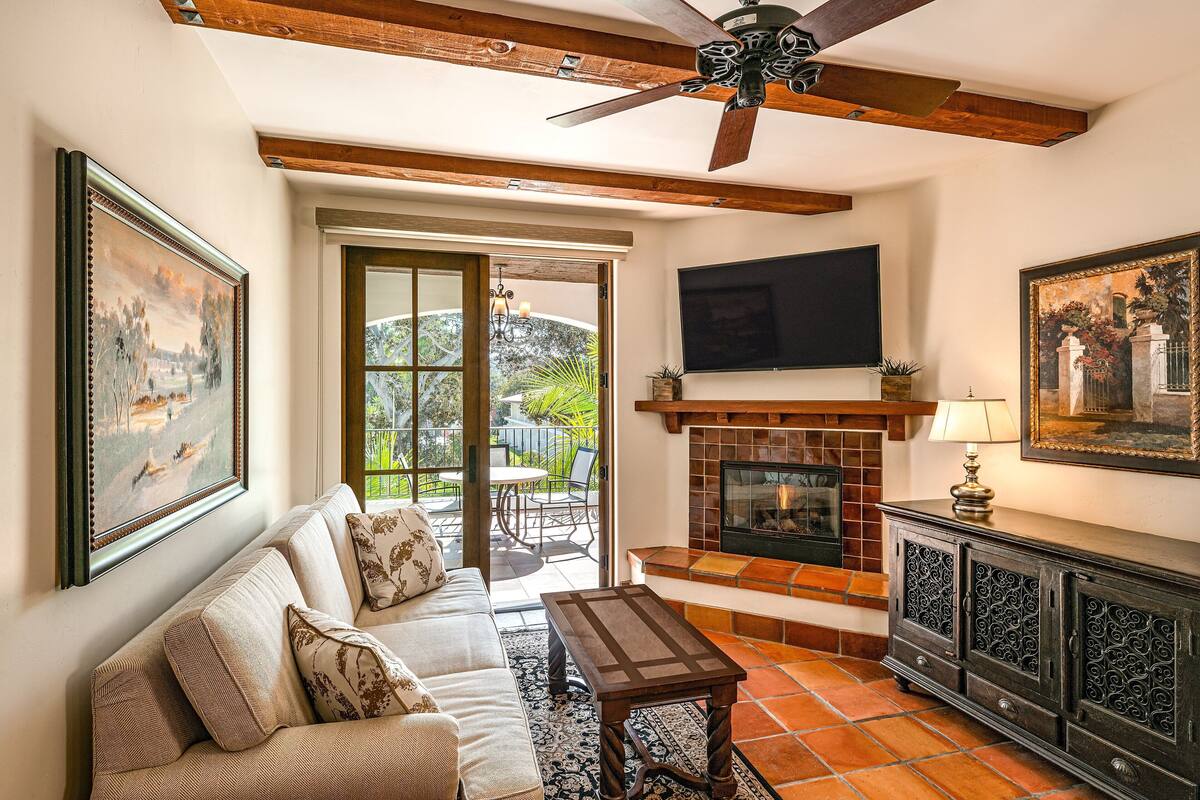 A living room with a sofa, coffee table, fireplace, and a ceiling fan.