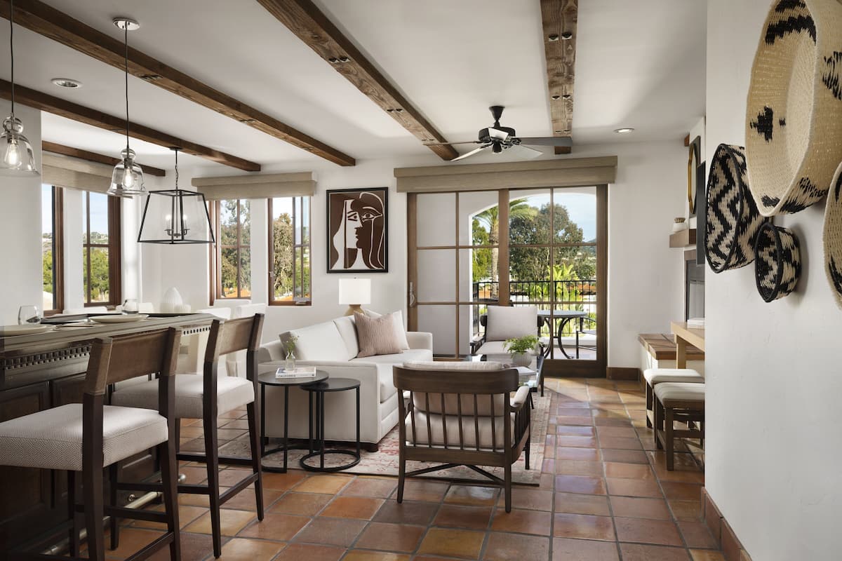 A spacious living area with a large window, a ceiling fan, and a dining area with a kitchen counter.