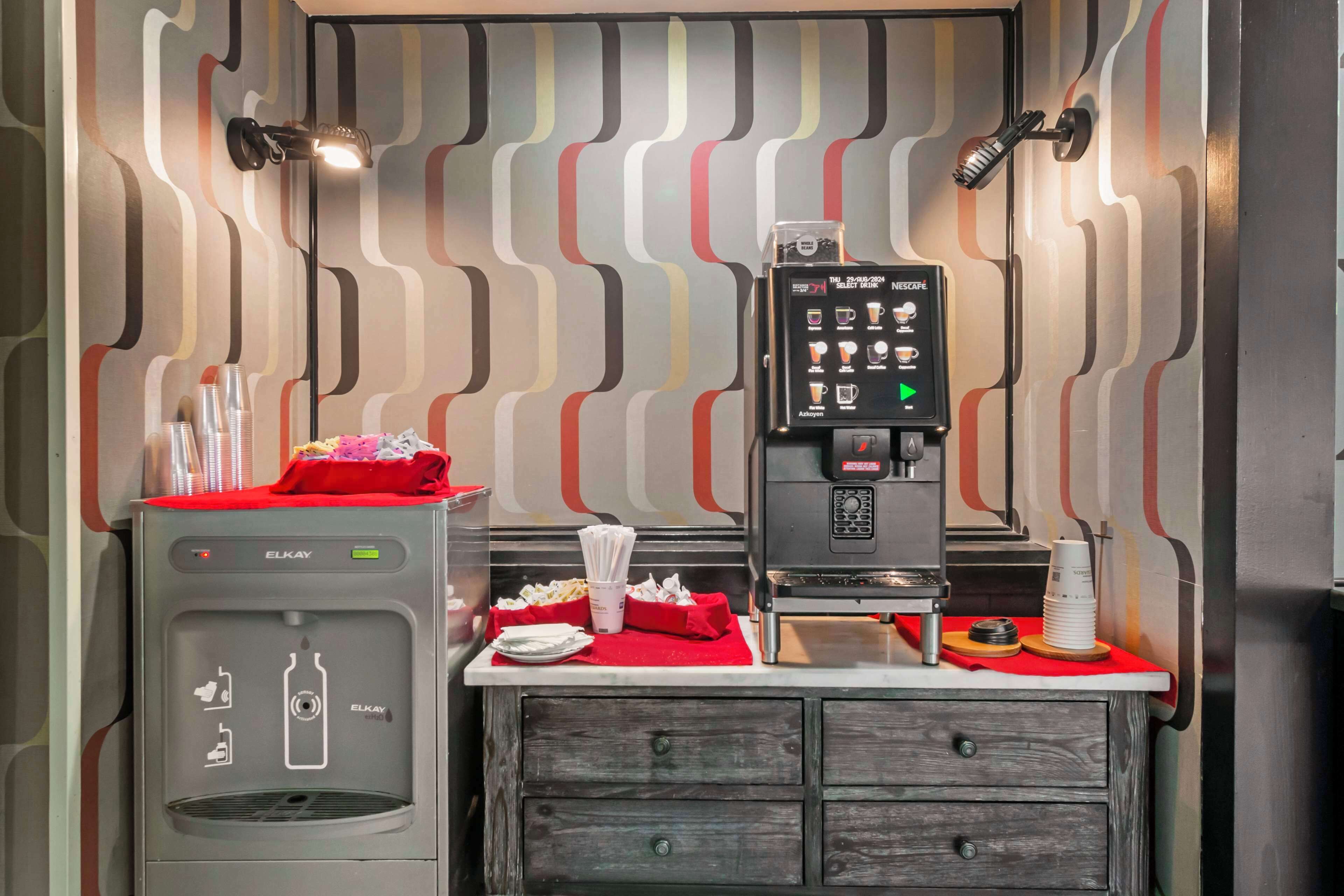 A kitchenette with a water dispenser, coffee machine, and a small counter with napkins and utensils.