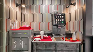 A kitchenette with a water dispenser, coffee machine, and a small counter with napkins and utensils.