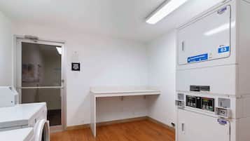 A laundry area with a washing machine, a drying rack, and stacked dryers.