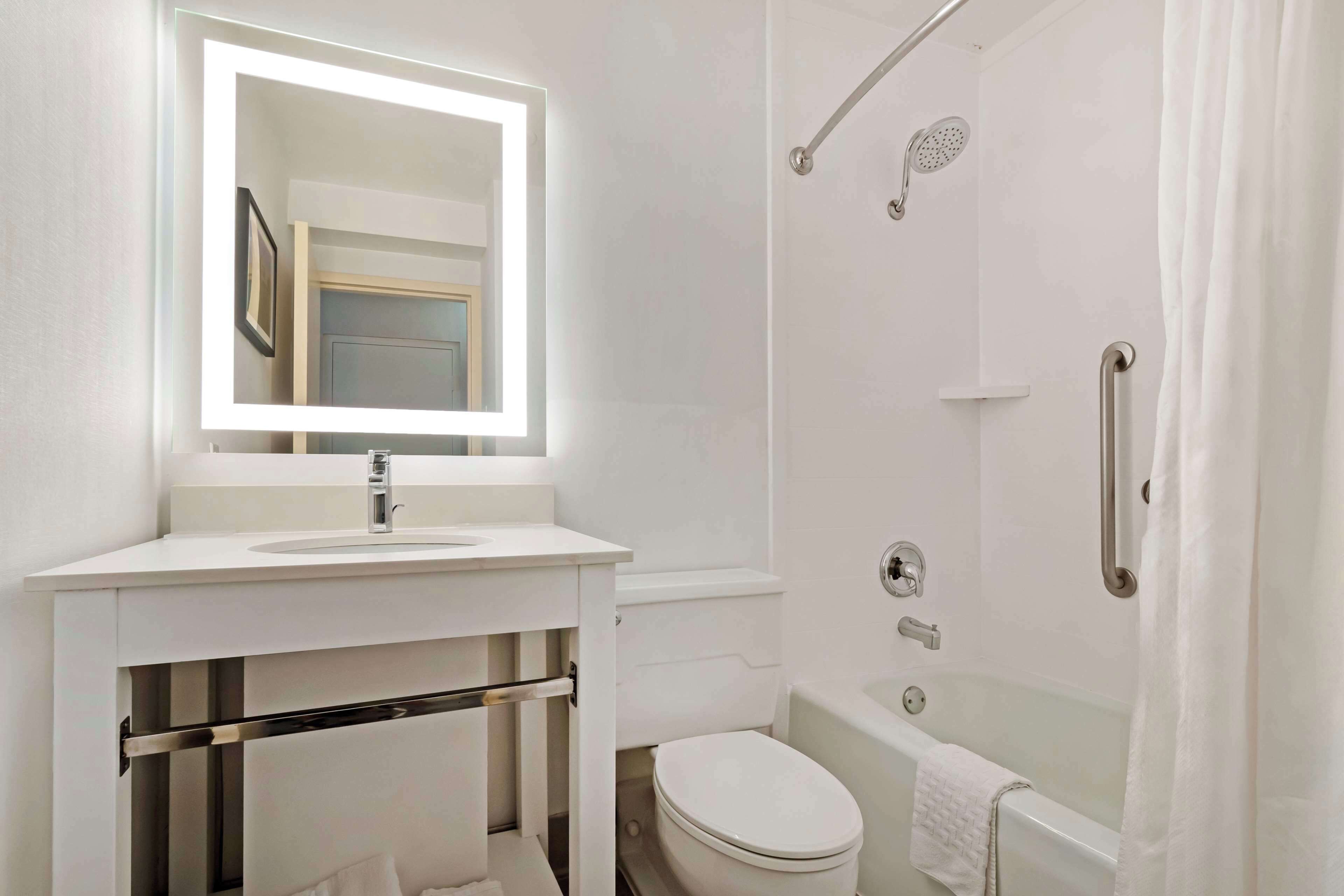 Un baño moderno con lavamanos, espejo y retrete blancos.