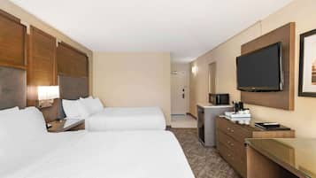 A hotel room with two beds, a desk, a television, and a minibar.