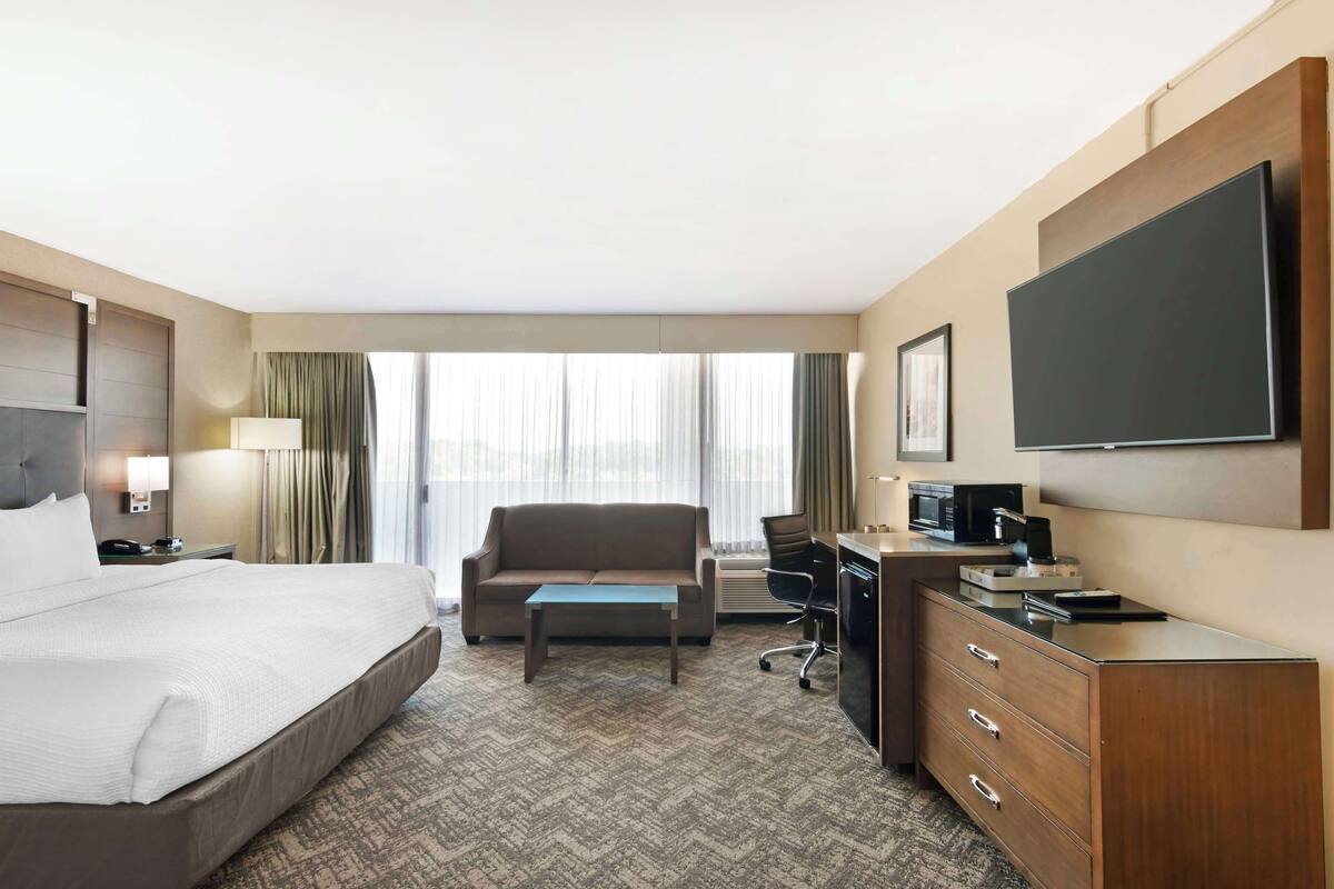A hotel room with a large bed, a desk with a computer, a chair, and a television.