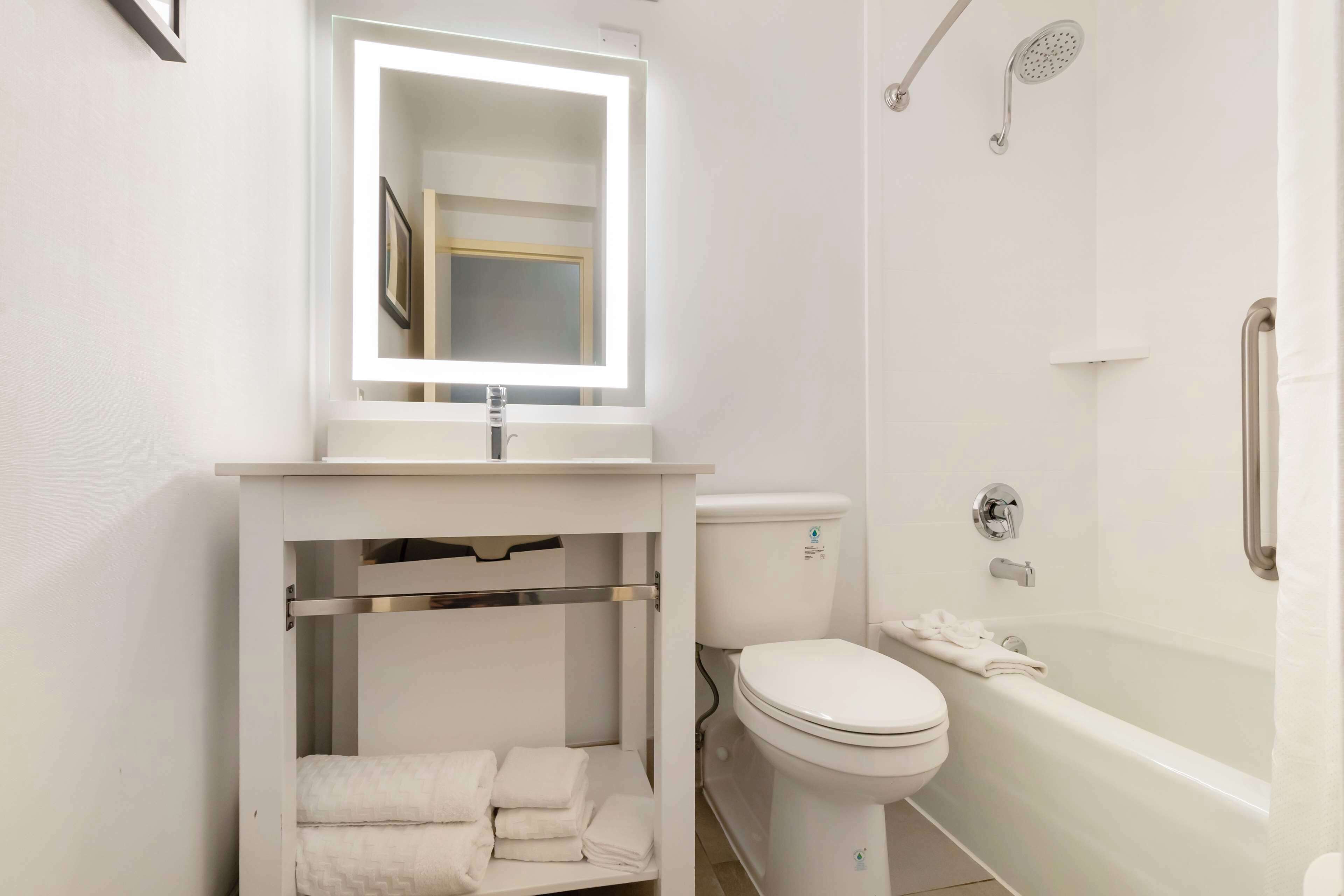 A bathroom with a white sink, mirror, toilet, and bathtub.