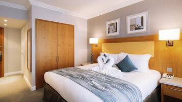 A hotel room with a large bed, wooden wardrobe, bedside lamps, and framed pictures on the wall.