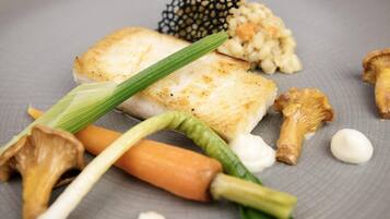 Un plato con un trozo de pescado, setas, zanahoria y vegetales verdes.