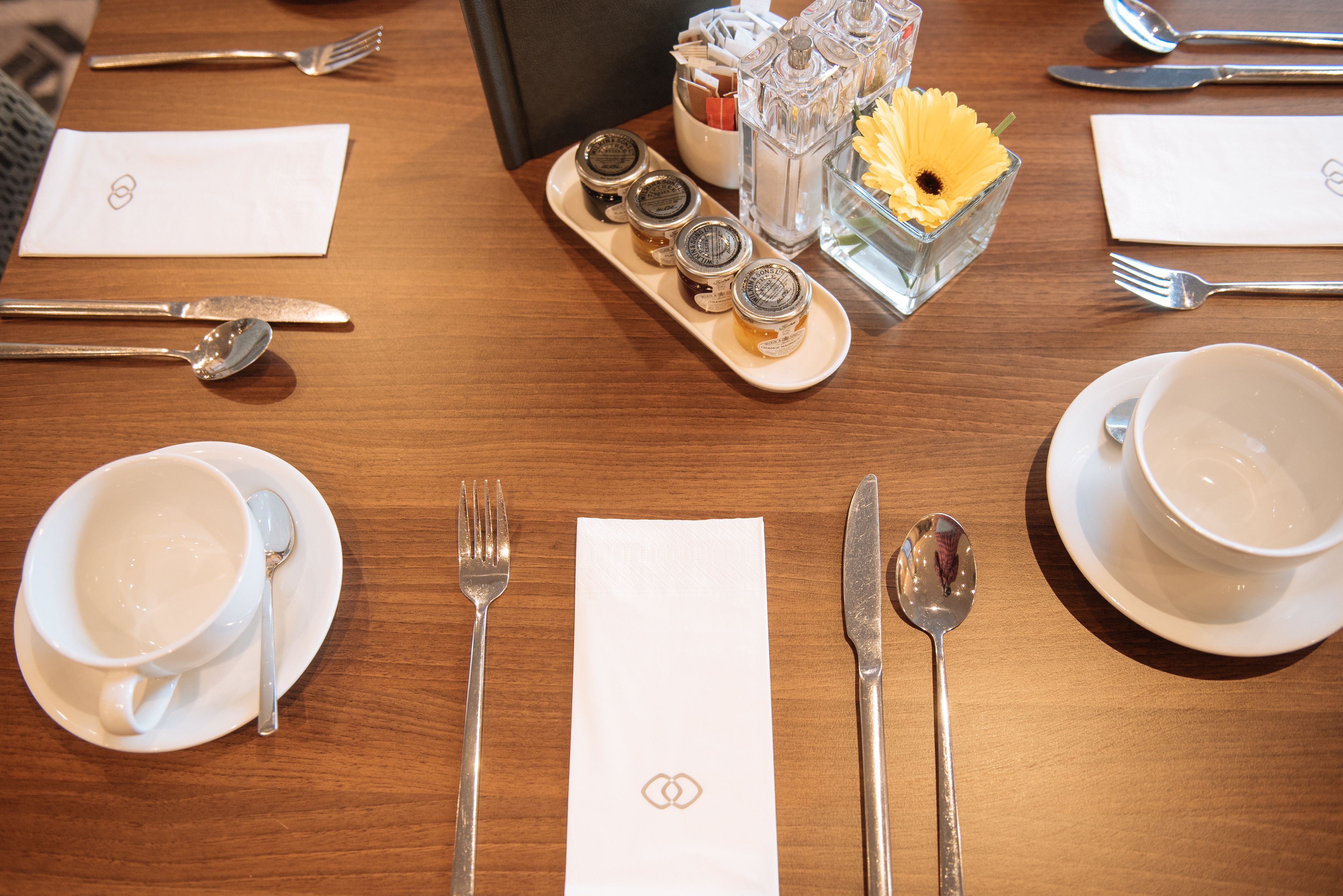 A neatly set dining table with plates, cutlery, and condiments.