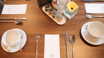 A neatly set dining table with plates, cutlery, and condiments.