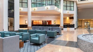 A spacious lobby with a central seating area, a reception desk, and a staircase connecting floors.