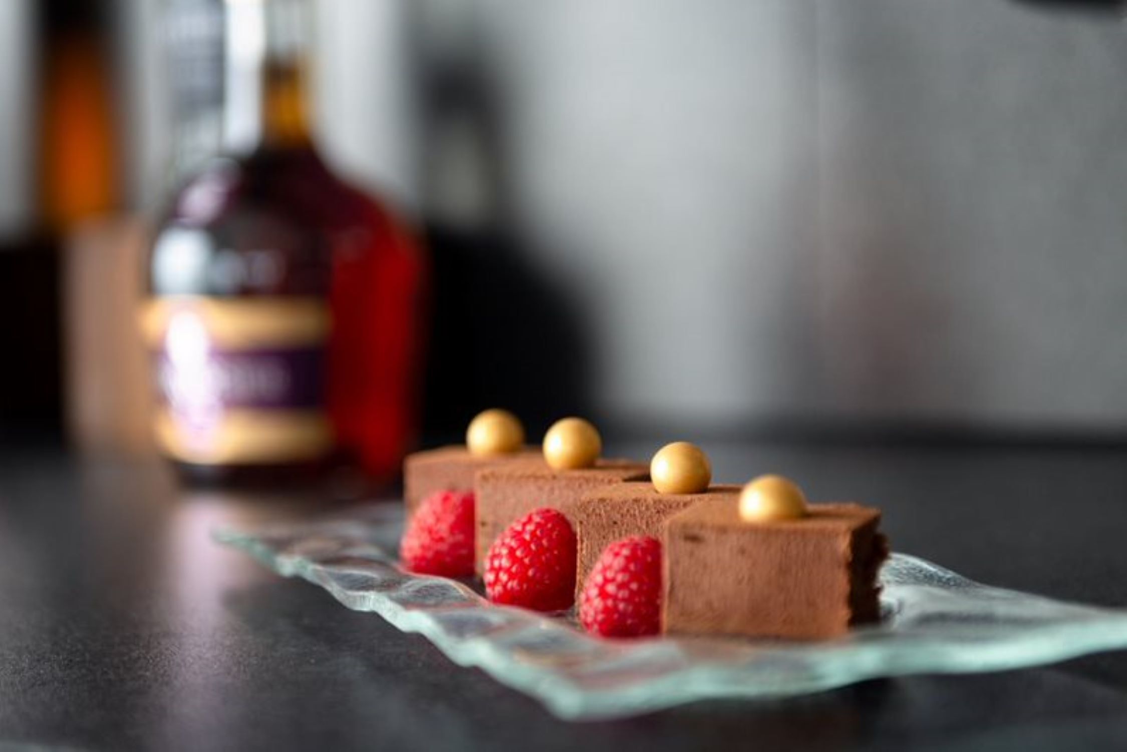 A dessert with chocolate mousse and raspberries on a glass plate.