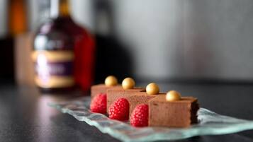 A dessert with chocolate mousse and raspberries on a glass plate.