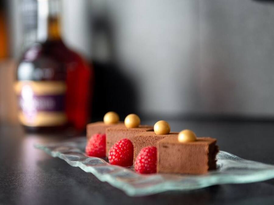 A dessert with chocolate mousse and raspberries on a glass plate.