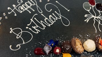 Une surface noire sur laquelle on a écrit en glaçage blanc : « Joyeux anniversaire ! », le tout entouré de friandises au chocolat et d’éléments décoratifs.